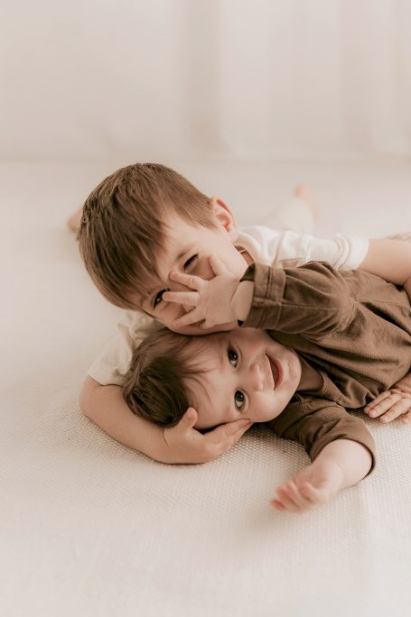 Niños jugando juntos en el suelo, sonriendo y abrazándose.