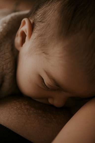 Bebé dormido sobre el brazo de un adulto, con expresión serena.