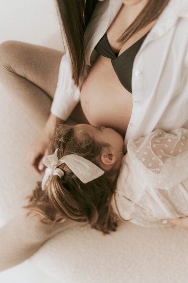 Mujer en blusa blanca sosteniendo a un bebé mientras ambos están sentados.
