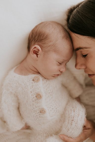 Madre y bebé acurrucados, ambos con expresiones de ternura y amor.