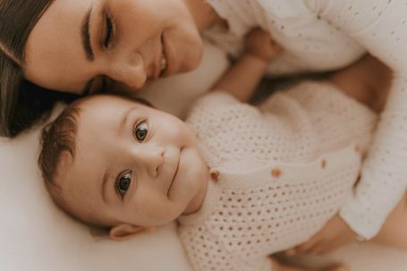 Una madre sonriente acurruca a su bebé, ambos en un entorno cálido y acogedor.